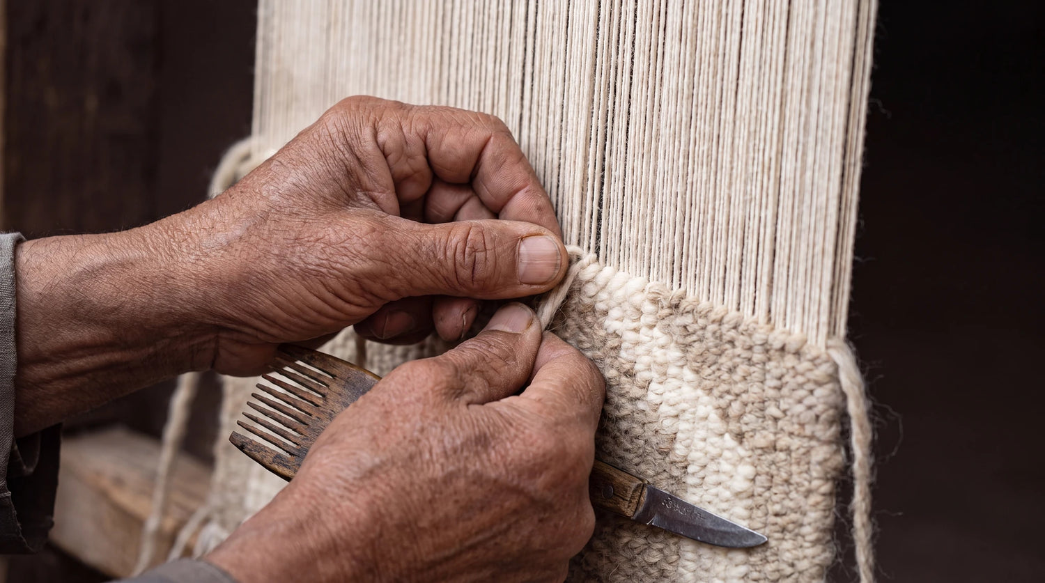 Hands weaving a Moroccan rug on a traditional loom
